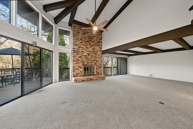 unfurnished living room with a fireplace, a towering ceiling, carpet floors, and plenty of natural light