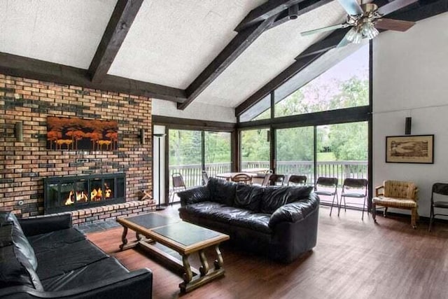 living room with a brick fireplace, a textured ceiling, hardwood / wood-style flooring, high vaulted ceiling, and beamed ceiling