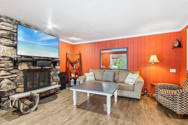 living room with a fireplace, wooden walls, light hardwood / wood-style flooring, and ornamental molding