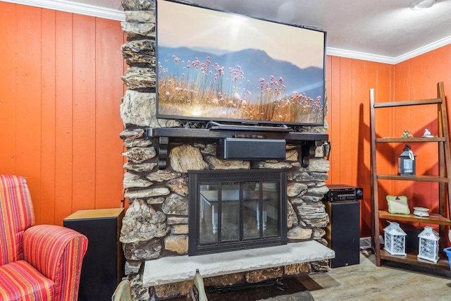 interior details with hardwood / wood-style floors, wooden walls, a stone fireplace, and crown molding