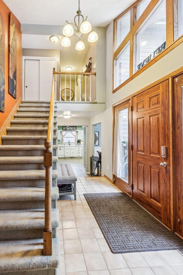 tiled entrance foyer featuring a chandelier, a high ceiling, and a textured ceiling