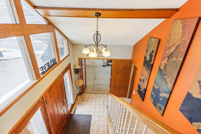 foyer with vaulted ceiling with beams, a textured ceiling, and an inviting chandelier