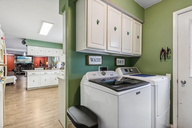 clothes washing area with cabinets, separate washer and dryer, and light hardwood / wood-style floors