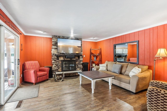 living room with hardwood / wood-style flooring, a fireplace, crown molding, and wooden walls