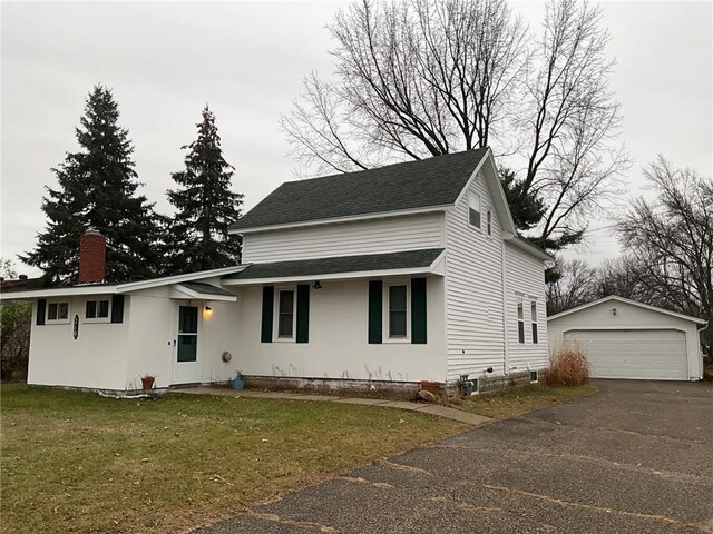 view of front facade featuring an outbuilding, a garage, and a front lawn