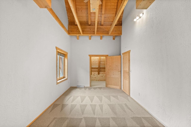 unfurnished room featuring vaulted ceiling with beams, light colored carpet, and wooden ceiling