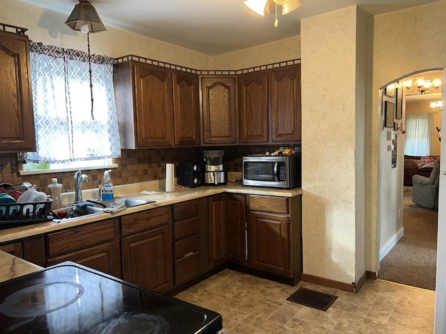 kitchen with backsplash, pendant lighting, sink, and light colored carpet