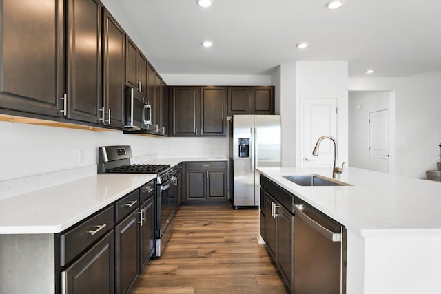 kitchen with sink, dark wood-type flooring, stainless steel appliances, and a center island with sink