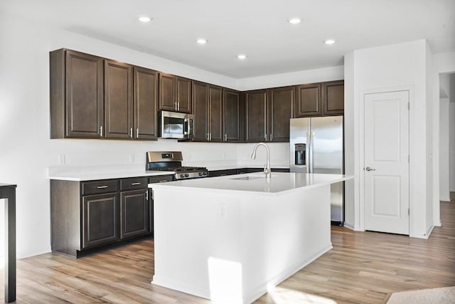 kitchen featuring stainless steel appliances, dark brown cabinets, sink, and light hardwood / wood-style flooring