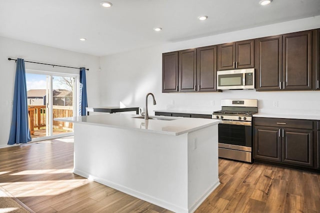 kitchen featuring stainless steel appliances, dark hardwood / wood-style floors, a kitchen island with sink, and sink