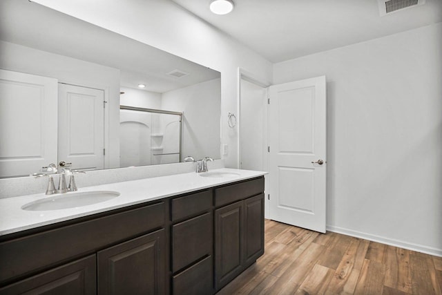 bathroom with vanity, a shower with shower door, and wood-type flooring