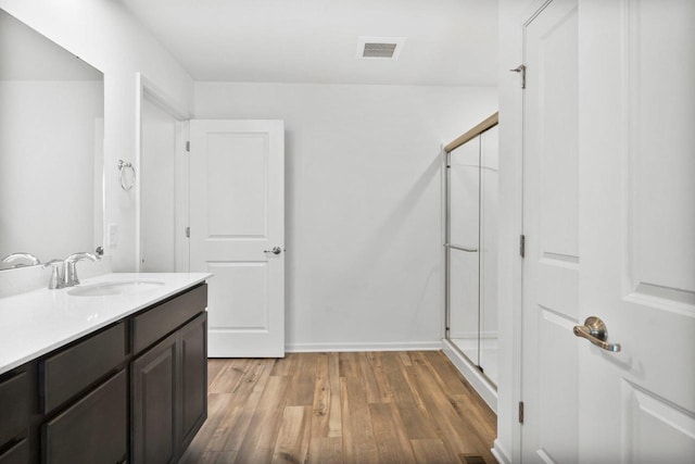 bathroom featuring walk in shower, wood-type flooring, and vanity