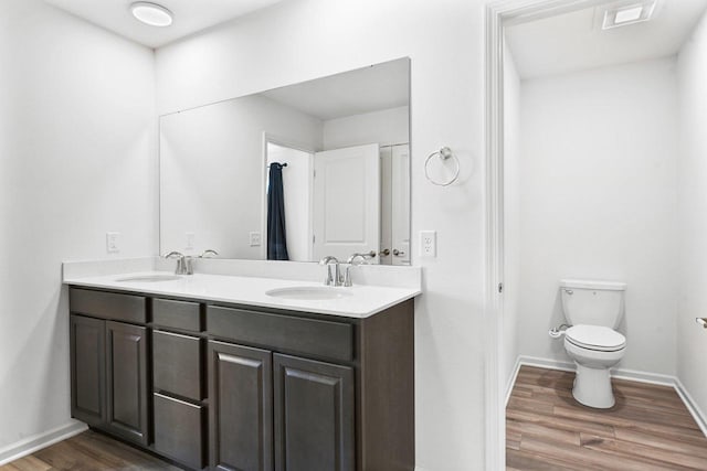 bathroom with wood-type flooring, vanity, and toilet