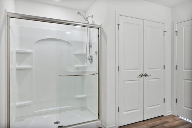 bathroom with a shower with shower door and wood-type flooring