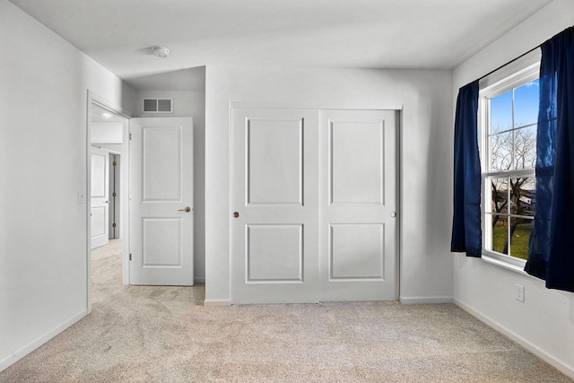 unfurnished bedroom featuring light colored carpet and a closet