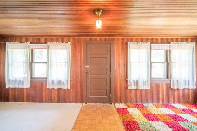 foyer featuring plenty of natural light, wooden walls, and light parquet flooring