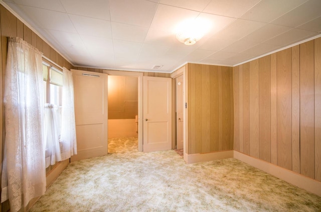 carpeted spare room featuring wooden walls