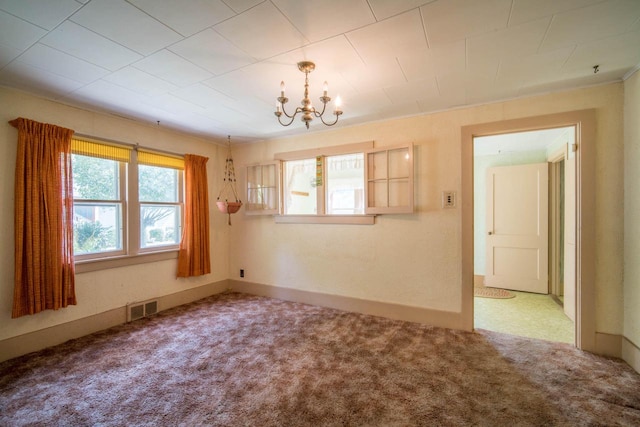 spare room featuring a notable chandelier and carpet floors