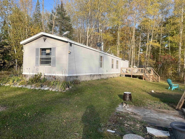 view of side of home with a wooden deck and a yard