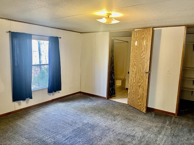 unfurnished bedroom featuring a walk in closet, carpet floors, and a textured ceiling