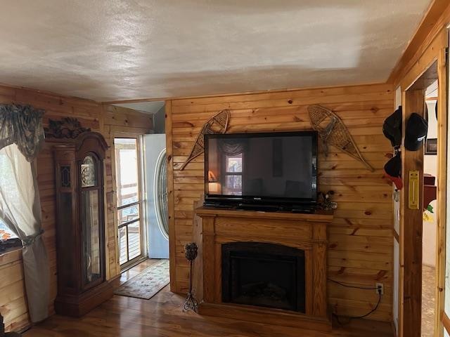 unfurnished living room featuring wooden walls, hardwood / wood-style floors, and a healthy amount of sunlight