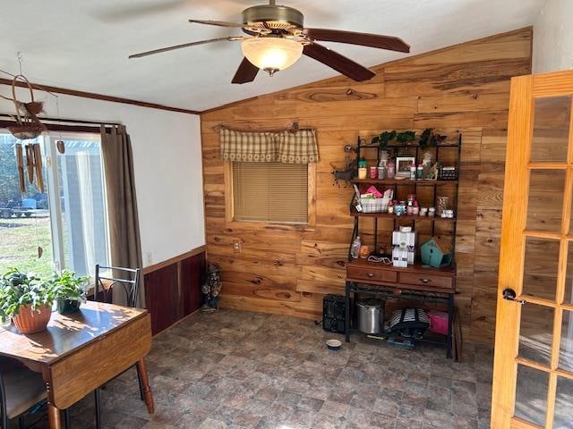 interior space featuring wood walls, ceiling fan, vaulted ceiling, and ornamental molding