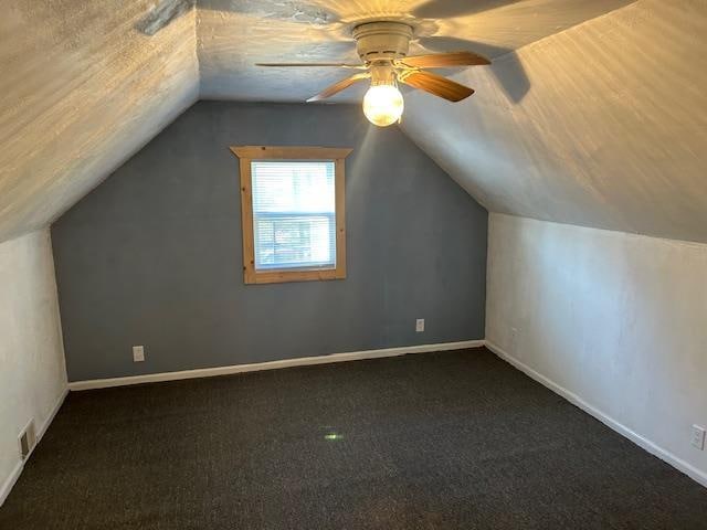 additional living space featuring ceiling fan, dark carpet, and lofted ceiling