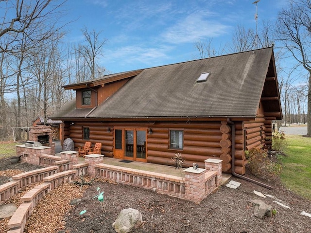 back of house featuring an outdoor stone fireplace and a patio