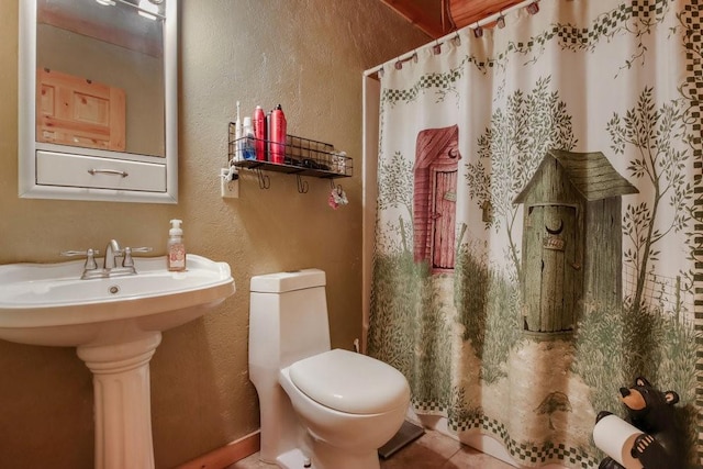 bathroom with tile patterned floors, sink, walk in shower, and toilet