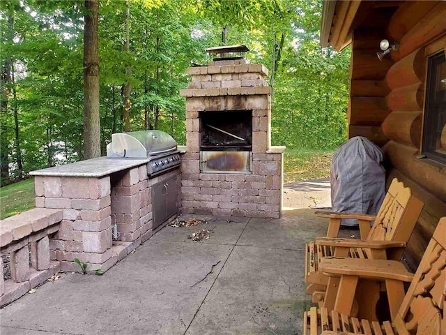 view of patio / terrace featuring a grill, an outdoor kitchen, and an outdoor stone fireplace