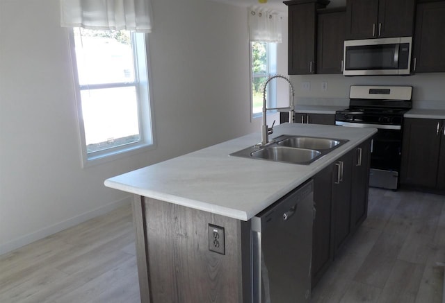 S13041 Shifflet Rd Unit 128, Spring Green, WI 53588 - kitchen featuring appliances with stainless steel finishes, a sink, light wood-style floors, light countertops, and an island with sink