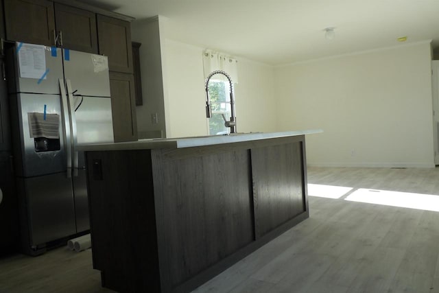 kitchen with stainless steel fridge with ice dispenser, an island with sink, and light hardwood / wood-style flooring