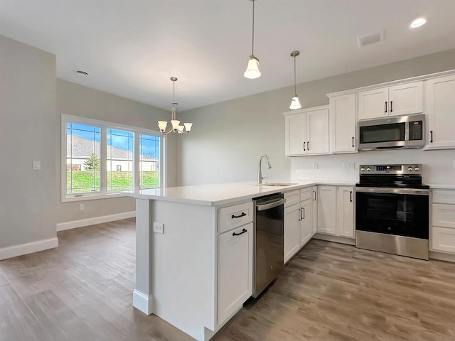 kitchen with white cabinets, pendant lighting, stainless steel appliances, and sink