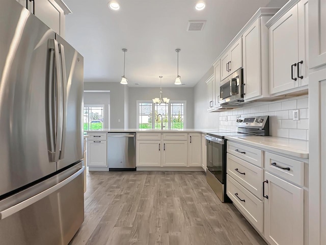 kitchen featuring an inviting chandelier, white cabinets, light wood-type flooring, appliances with stainless steel finishes, and decorative light fixtures