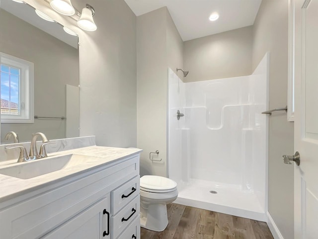 bathroom featuring hardwood / wood-style flooring, vanity, toilet, and a shower