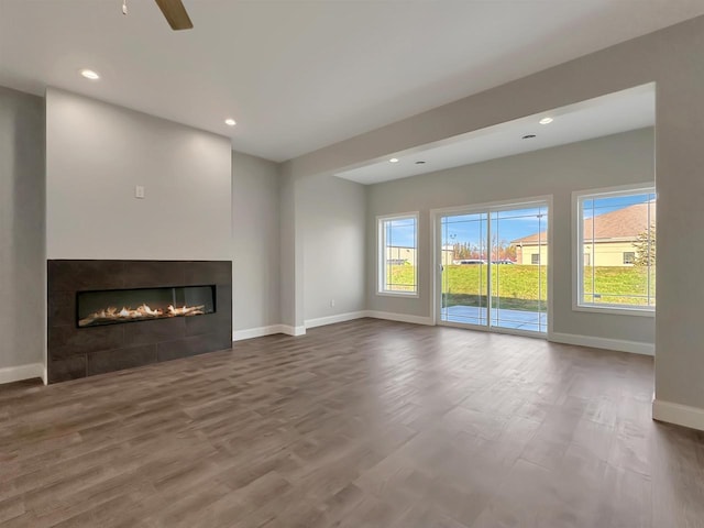 unfurnished living room featuring a tile fireplace, ceiling fan, and hardwood / wood-style floors