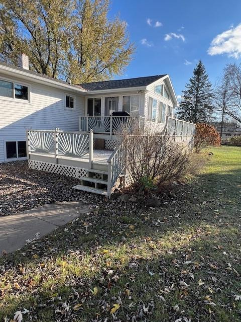 back of property with a wooden deck and a yard