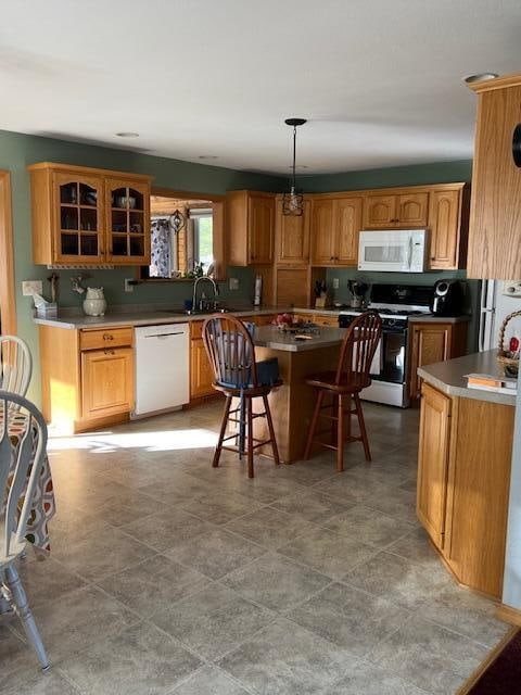 kitchen with a kitchen breakfast bar, a center island, pendant lighting, and white appliances