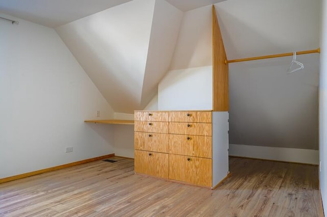 bonus room with lofted ceiling and light wood-type flooring