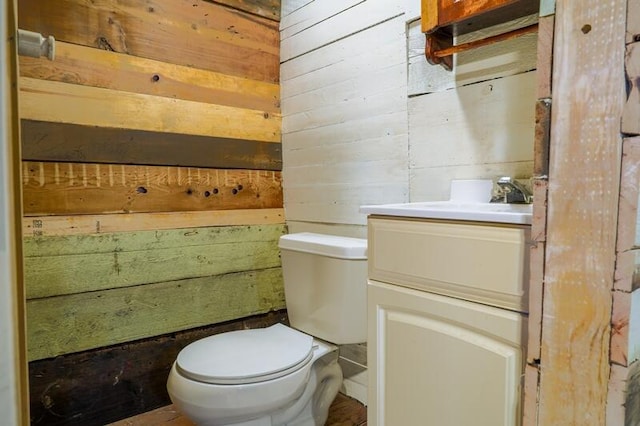 bathroom featuring vanity, toilet, and wood walls