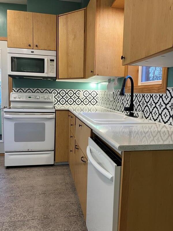 kitchen featuring backsplash, sink, light tile patterned floors, and white appliances