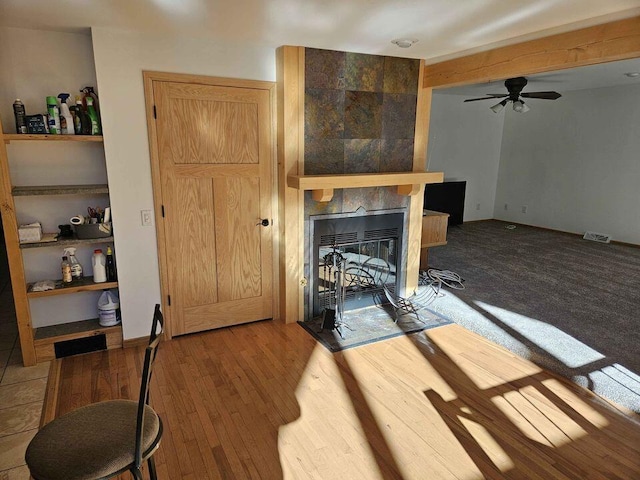 living room featuring a fireplace, light wood-type flooring, and ceiling fan