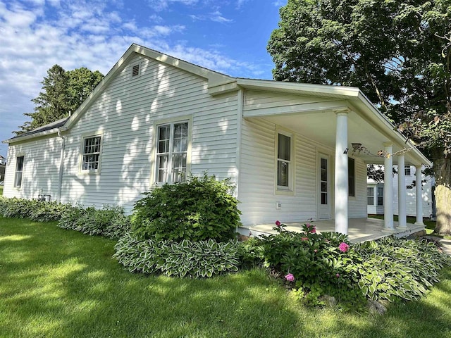 view of home's exterior with a lawn and covered porch