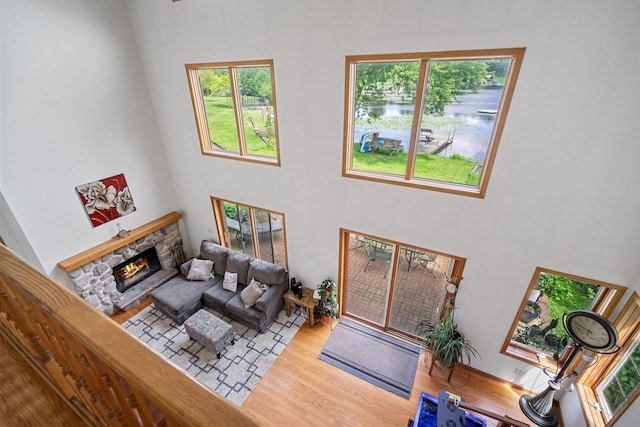 living room featuring a towering ceiling, light hardwood / wood-style flooring, and a stone fireplace