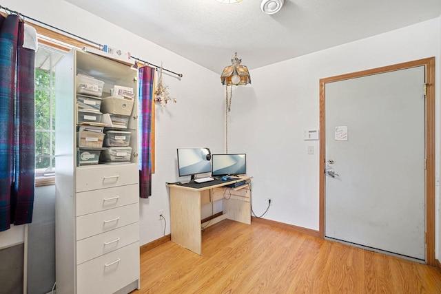 home office with a textured ceiling and light wood-type flooring