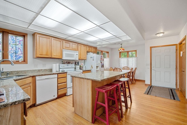 kitchen with sink, a center island, white appliances, and light wood-type flooring