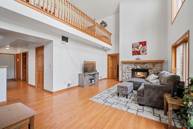 living room featuring a fireplace, a towering ceiling, and light wood-type flooring