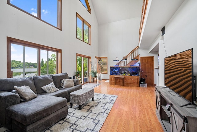 living room with a water view, a wealth of natural light, hardwood / wood-style floors, and high vaulted ceiling