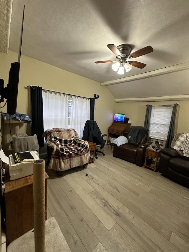 living room with lofted ceiling, ceiling fan, light hardwood / wood-style floors, and a textured ceiling