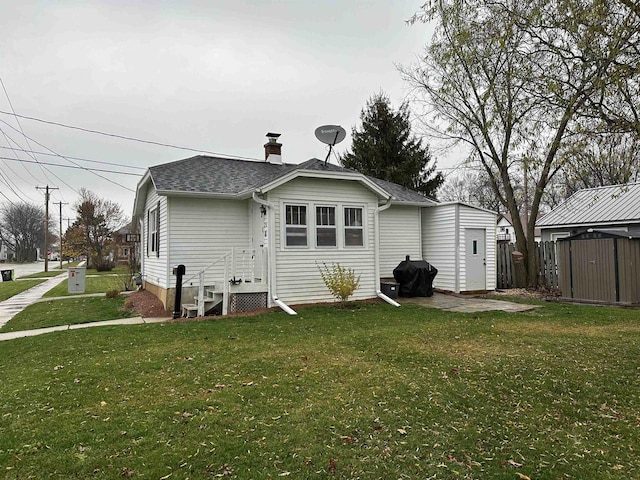 back of property with a yard and a storage shed